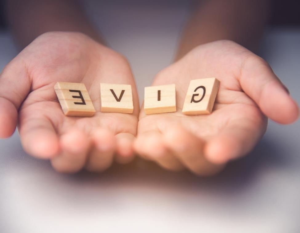 hands with give wooden letter tiles